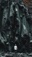 Person standing before a large basalt rock formation photo