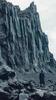 Figure stands at the base of a colossal rock formation photo