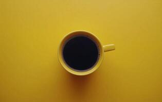 Warm black coffee in a bright yellow cup on a vibrant yellow background photo