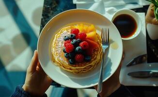 Delicious pancakes topped with fresh berries and fruit served with coffee in a cozy setting photo