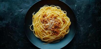 Delicious spaghetti with meat sauce served in black bowl on dark background photo