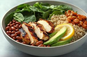 A bowl of food with chicken, avocado, spinach and beans photo