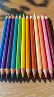 Colorful pencils arranged neatly on a wooden surface for artistic activities or classroom use photo
