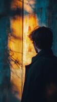 A man standing in front of a wall with the sun shining through it photo
