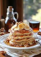Delicious stacked pancakes with bananas and walnuts served with maple syrup and coffee photo
