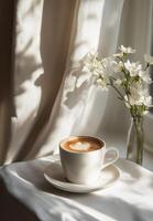 Warm coffee cup on a table by the window with flowers during sunlight photo