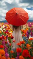 Woman with red umbrella standing in vibrant flower field during a bright sunny day photo