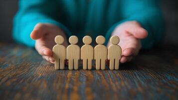 Hands holding wooden figures representing teamwork and collaboration on a wooden table photo