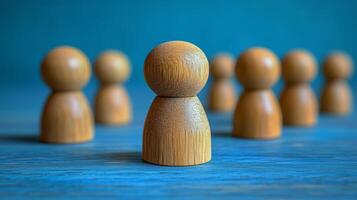 Wooden figures arranged on a blue background creating a focus on the central piece photo