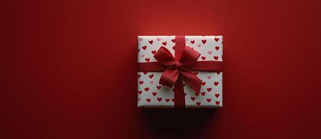 Red gift box with heart patterns on a red background, perfect for celebrations and special occasions photo