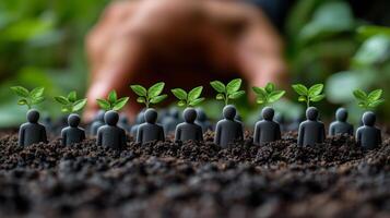 Small figurines with green sprouting plants in soil and hand reaching out in lush garden photo