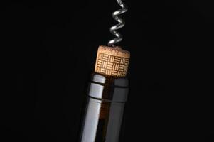 Wine bottle and corkscrew captured in elegant detail against a dark background photo