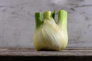 Unique fennel bulb resting on a rustic wooden table with a subtle background in soft natural light photo