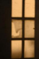 Soft sunlight filters through a weathered window casting shadows in a quiet room photo