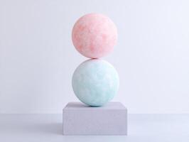 Two pastel colored spheres balanced on a concrete cube photo