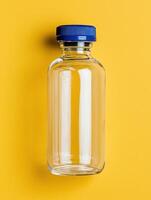 Empty glass bottle with blue cap on yellow background photo