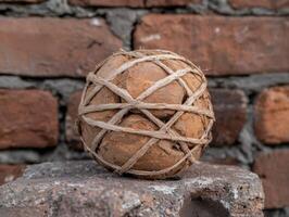 A ball made of rocks and string sits on a stone surface photo