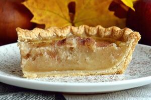A slice of custard pie with autumn leaves in the background photo