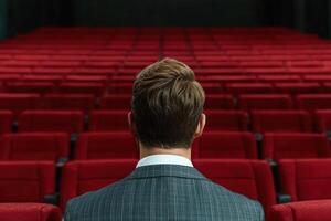 Man in a suit sitting in an empty theater photo