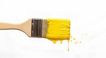 Paintbrush with fresh yellow paint splatter on white background Clean image of a paintbrush with yellow paint splatters on a white background great for art projects or creative content photo