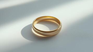 Elegant golden ring rests on a light surface casting a soft shadow during daylight hours photo