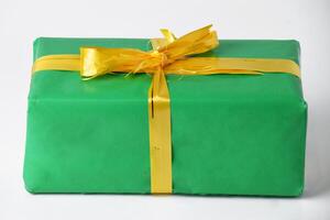 Closeup view Green gift box with golden yellow ribbon on a white background photo
