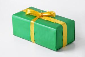 Green Gift Wrapped with a Luxurious Golden Bow on a White Backdrop photo
