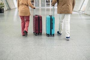 unrecognizable Senior couple walking through airport terminal pulling suitcases photo