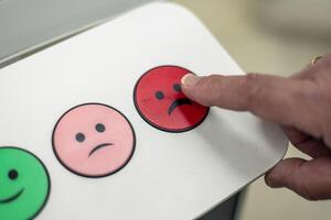 Customer pressing red button with sad emoticon for negative feedback closeup photo