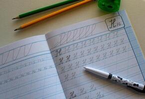View of a notebook for practicing writing letters, notebook and pencils photo