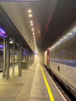 Passenger train awaits evening departure on a railway platform in the fog photo