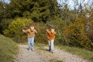 Two boys run to race on a dirt road in the forest. Siblings connection photo
