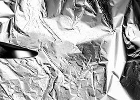 High-contrast crumpled aluminum foil texture with reflective and wrinkled details, perfect for abstract designs. photo