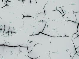 Abstract texture featuring a cracked and weathered surface with irregular black lines on a light background. photo