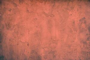 Close-up of a rustic red plaster wall texture with rough and uneven patterns, ideal for design backdrops. photo