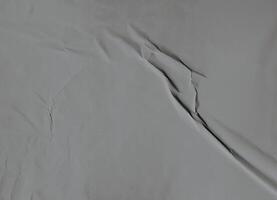 Minimalistic gray wrinkled paper texture with soft folds and subtle surface details. photo