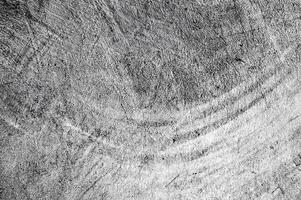 Black and white close-up of a textured surface with scratches and curved patterns, ideal for abstract backgrounds. photo