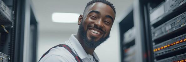 Technician stands confidently in a data center, showcasing servers while smiling at the camera photo