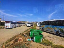 Mecca, Saudi Arabia on 24 February 2024. Parked Tour Buses Sunny Day Landscape Green Bins photo