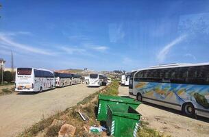Mecca, Saudi Arabia on 24 February 2024. Tour Buses Parked Sunny Dayside Dirt Lot Scenic View photo