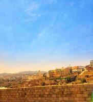 Taif, Saudi Arabia on 24 February 2024. Clear Blue Sky Over Buildings Brown Brick Wall View photo