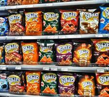 Madinah, Saudi Arabia on 28 February 2024. Colorful Bugles Snack Bags Variety Store Shelf Display photo