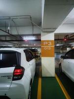 Jakarta, Indonesia on 21 March 2024. White Hatchback Car Parked Underground Garage Level P3 Q13 photo