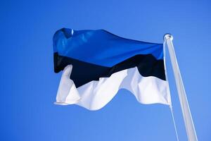 National Estonian flag waving against a clear blue sky, symbolizing national pride and identity with distinct horizontal blue, black, and white stripes. Copy space 1 photo