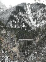 a suspension bridge between two snow-capped mountains photo