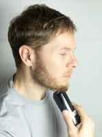 a man trims his beard with a trimmer. An electric razor trimming a beard. photo