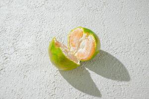 a green orange gradient citrus fruit isolated on a textured white background, showcasing its vibrant color transition photo