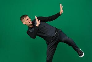 dissatisfied man pushes away with his hands emotions of a handsome man guy on a green background chromakey close-up dark hair young man photo