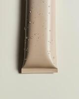 A tube of cream with water droplets on it photo