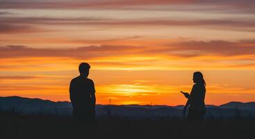 Silhouette Couple Watching a Breathtaking Sunset Over Mountain Ranges photo